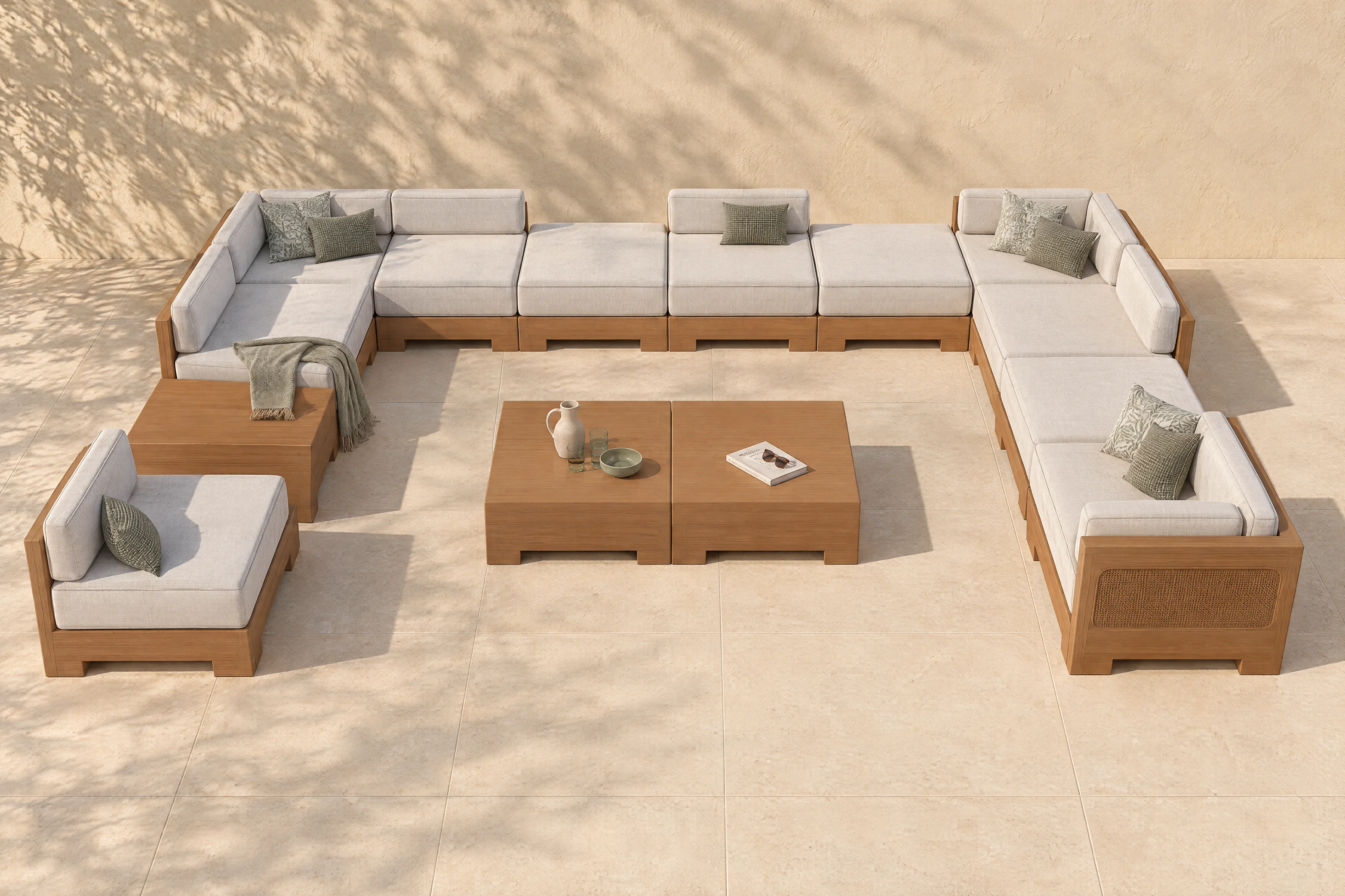 A Nasim arrangement in the founder's own U on a limestone terrace, Cast Silver cloth on honey-coloured timber with matching woven cane panels, no one there, the shadow of an olive tree on the plaster wall.