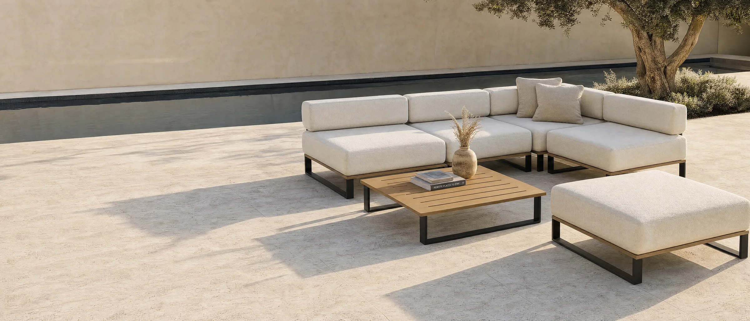 A Nour arrangement on a sheltered terrace: a corner of 800 millimetre modules with a slatted teak table and a single pouf, against a pale wall.